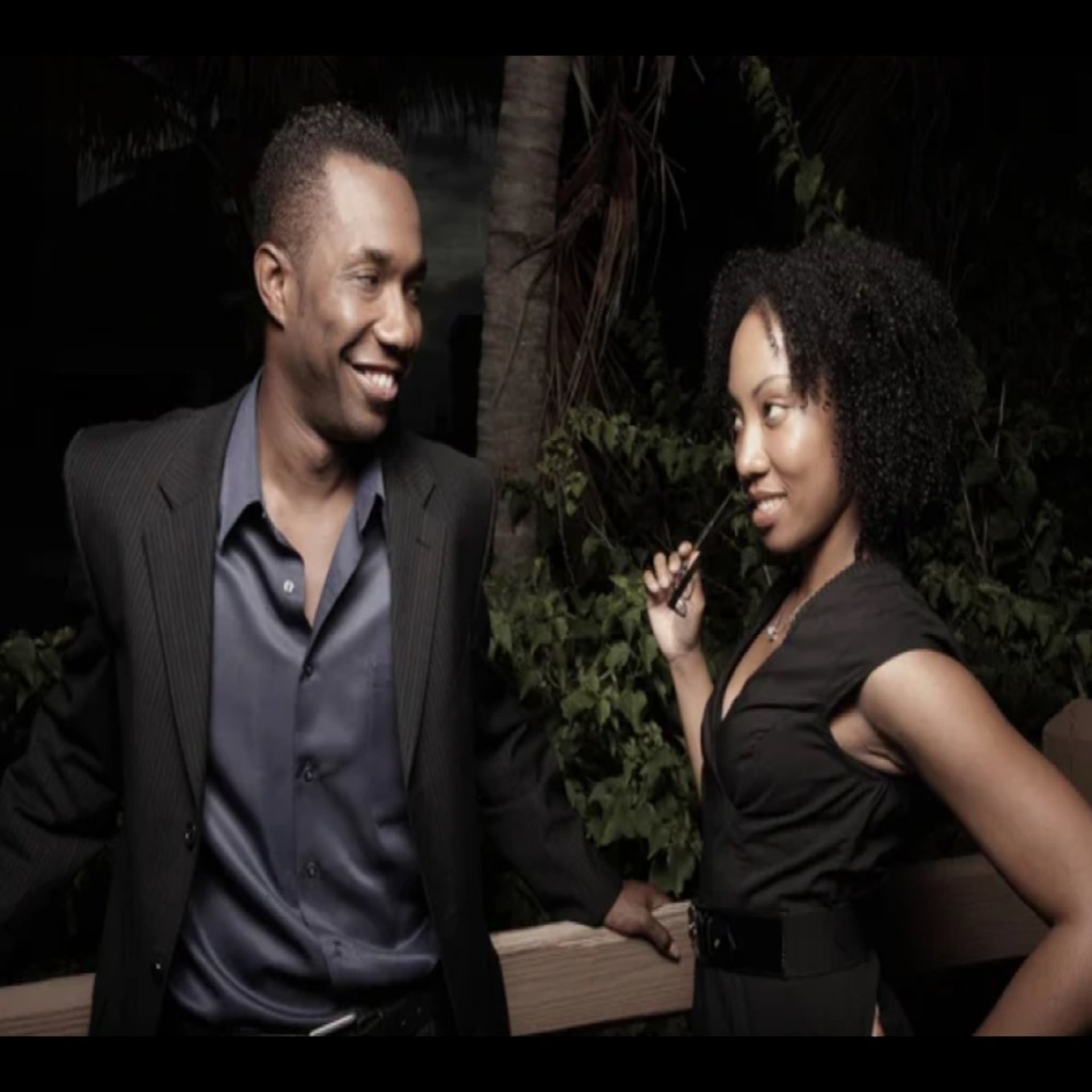 black woman looking flirtatiously at a black man, who's smiling at her