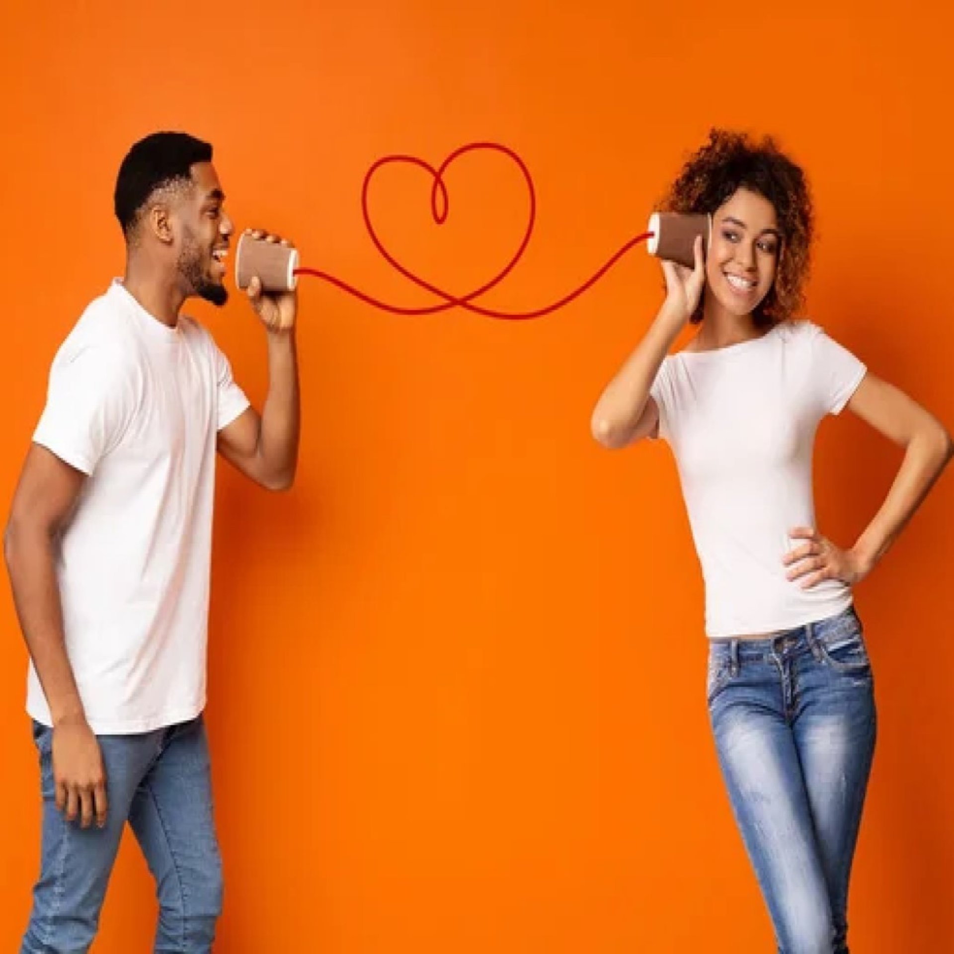 man and woman young black couple standing, using cups as phones. a heart shaped line connects them. orange background