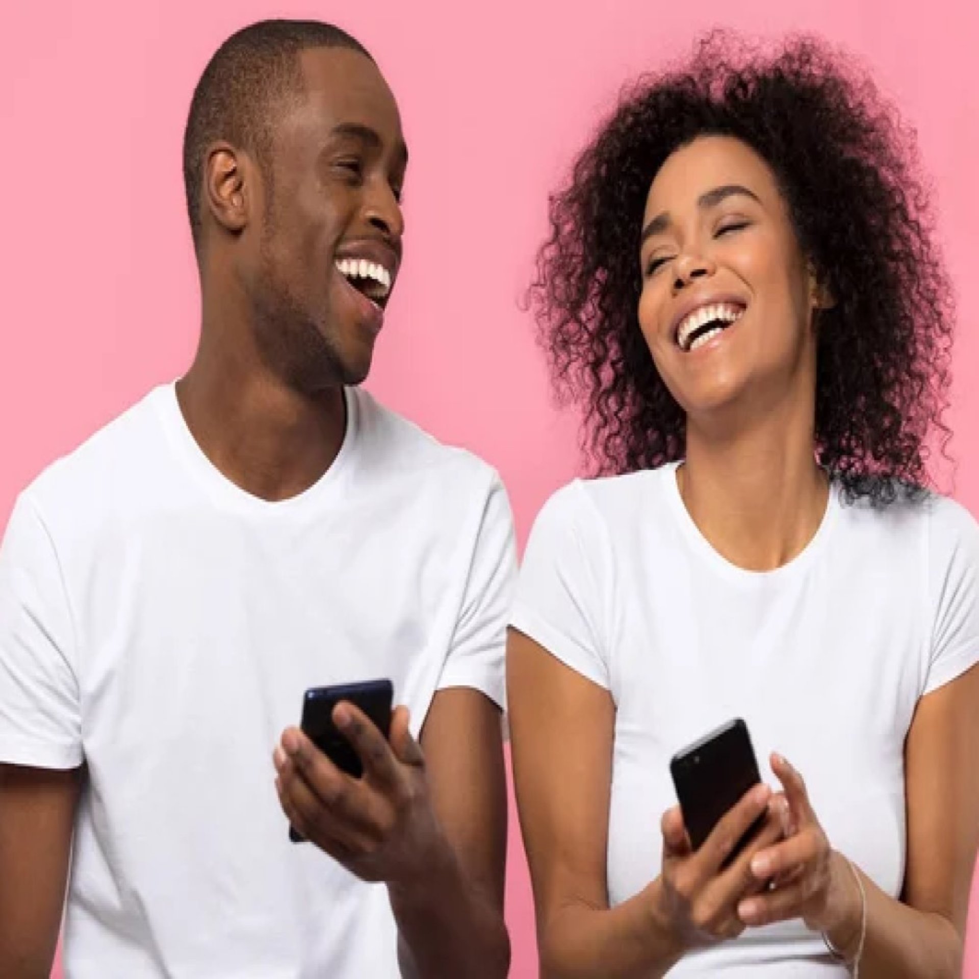 man and woman black young couple using cell phones sitting side by side laughing. pink background