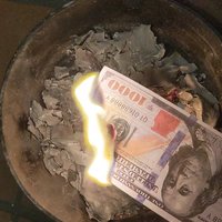 a joss paper note with a burning corner edge over a pot of ashes 